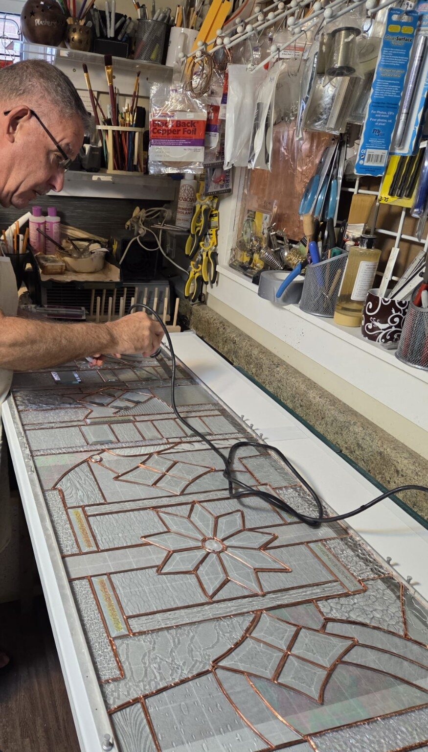 Paul working on a large stained-glass panel at his studio bench
